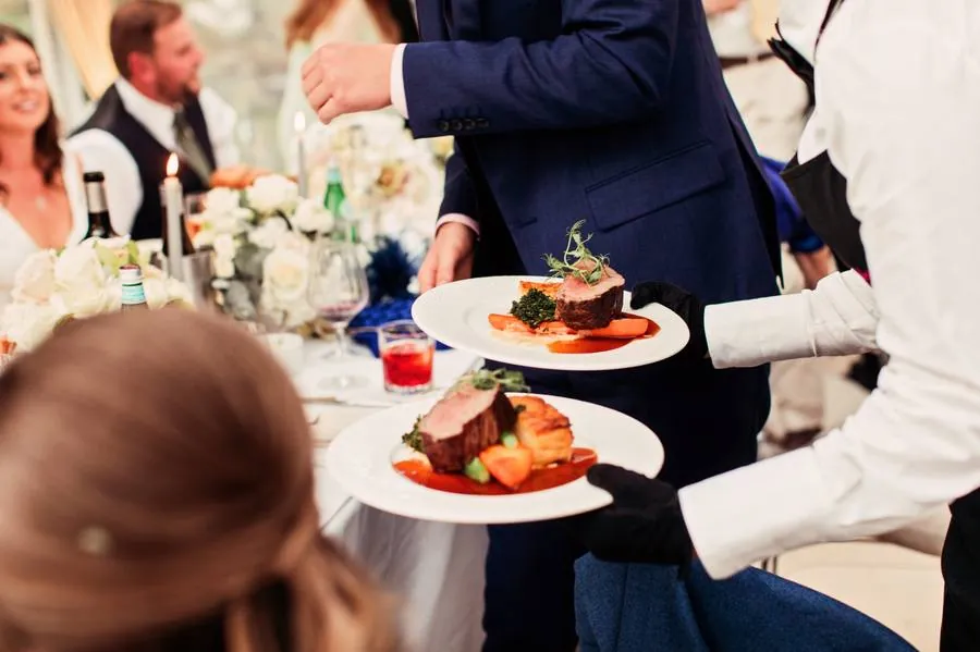 Beef main course plates being served at the table during the wedding breakfast