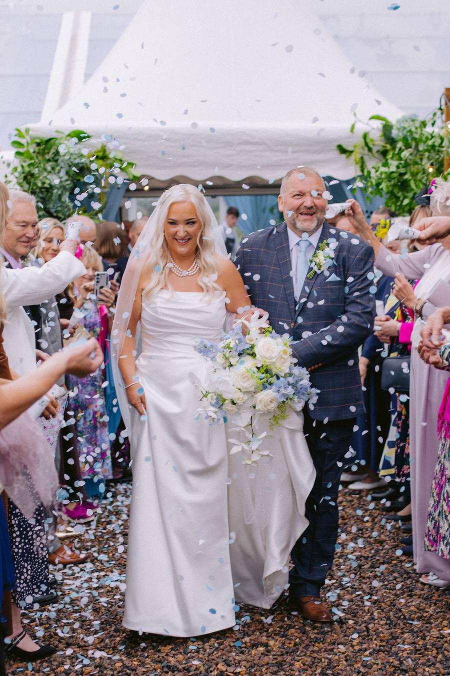 Bride and groom walking through blue confetti