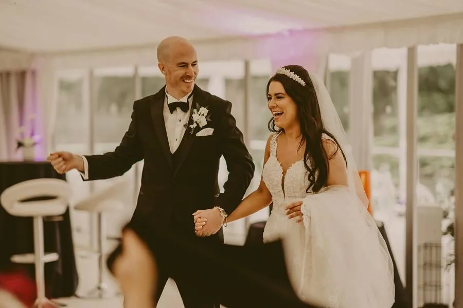 Couple laughing as they walk into the marquee hand in hand