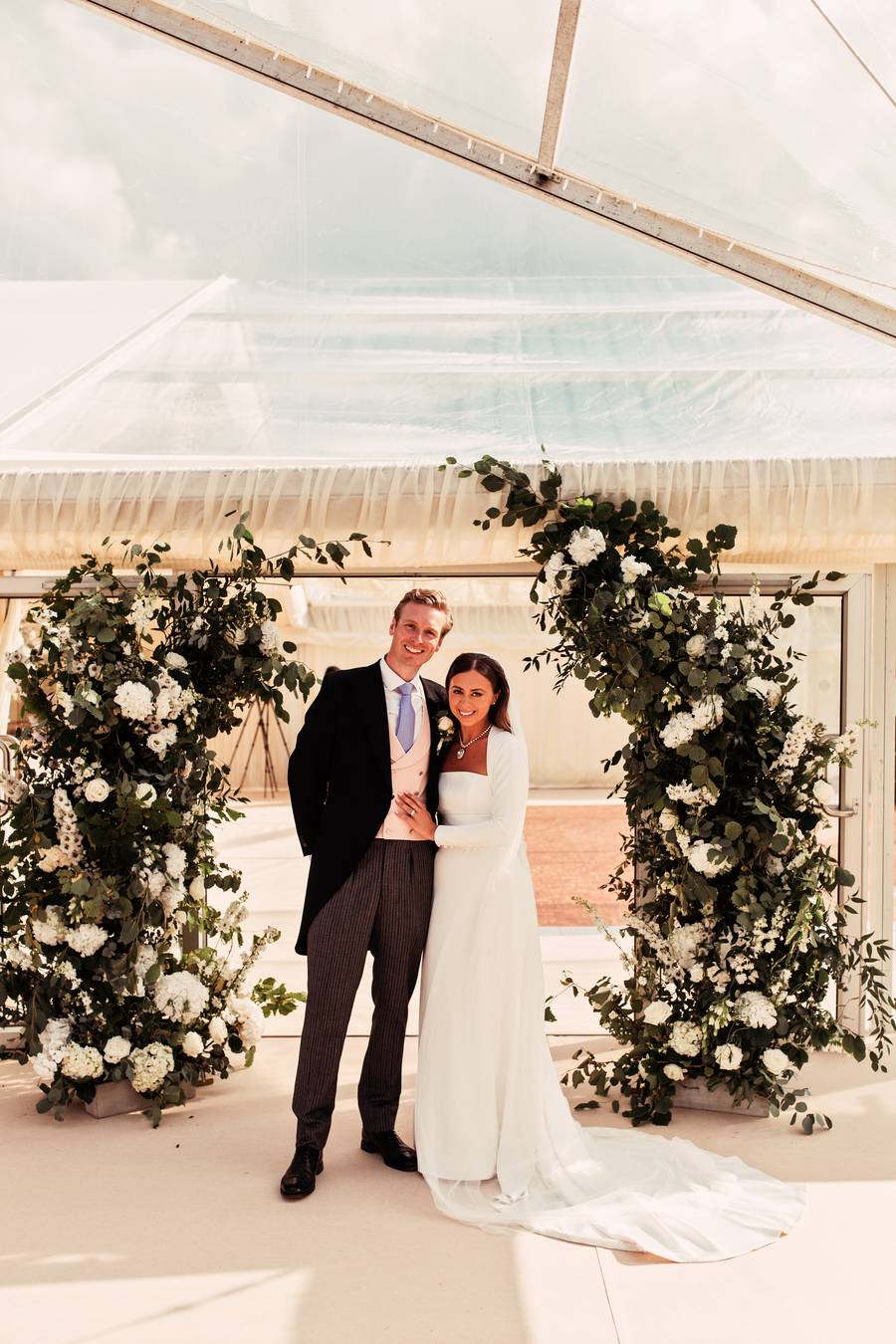 Couple standing between two floral columns at the marquee entrance