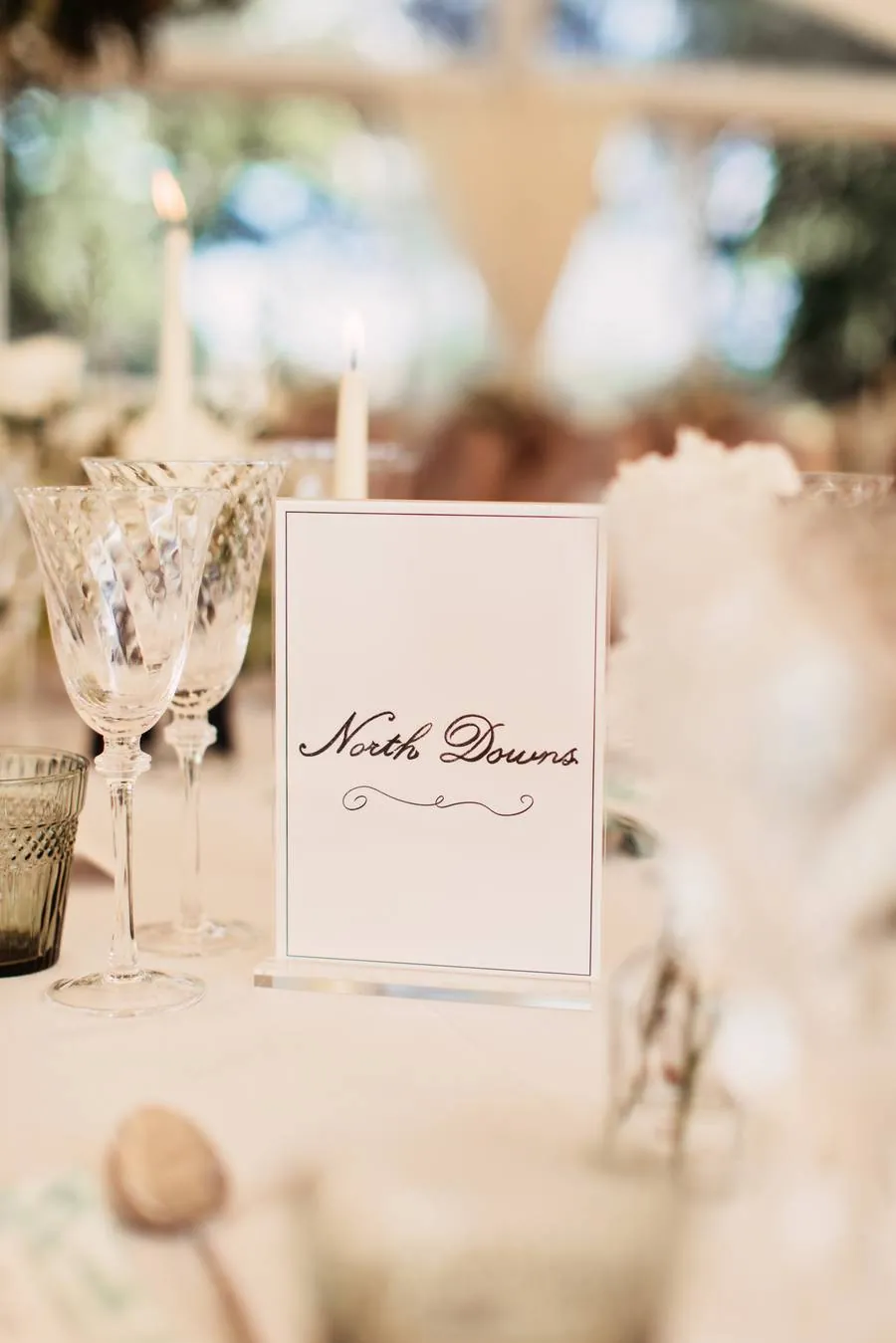 Handwritten table name card among crystal glasses