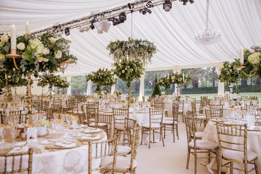 Interior with gold chairs, tall flower stands and a hanging floral ring