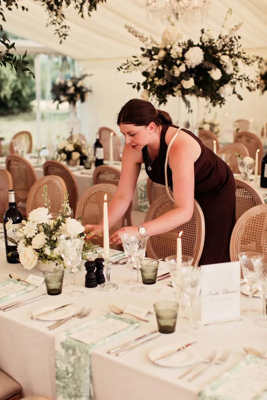 Kate adjusting flowers and candles on a table with rattan chairs