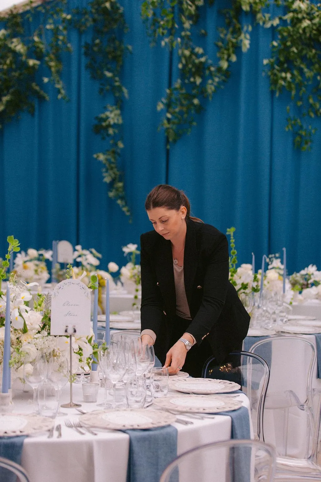 Kate setting a table in a marquee with blue draping