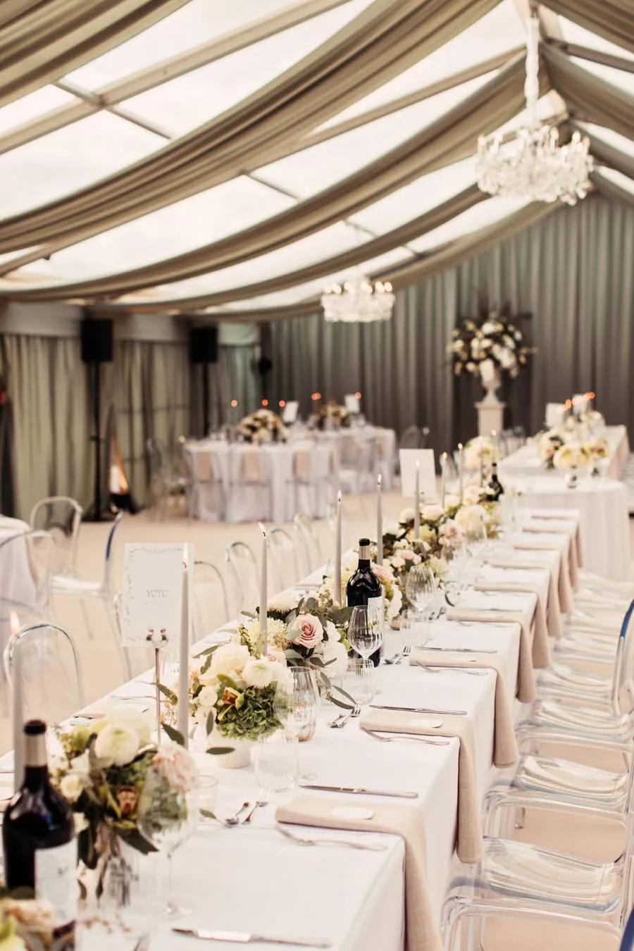 Long table with grey candles and low flowers beneath a sage draped ceiling