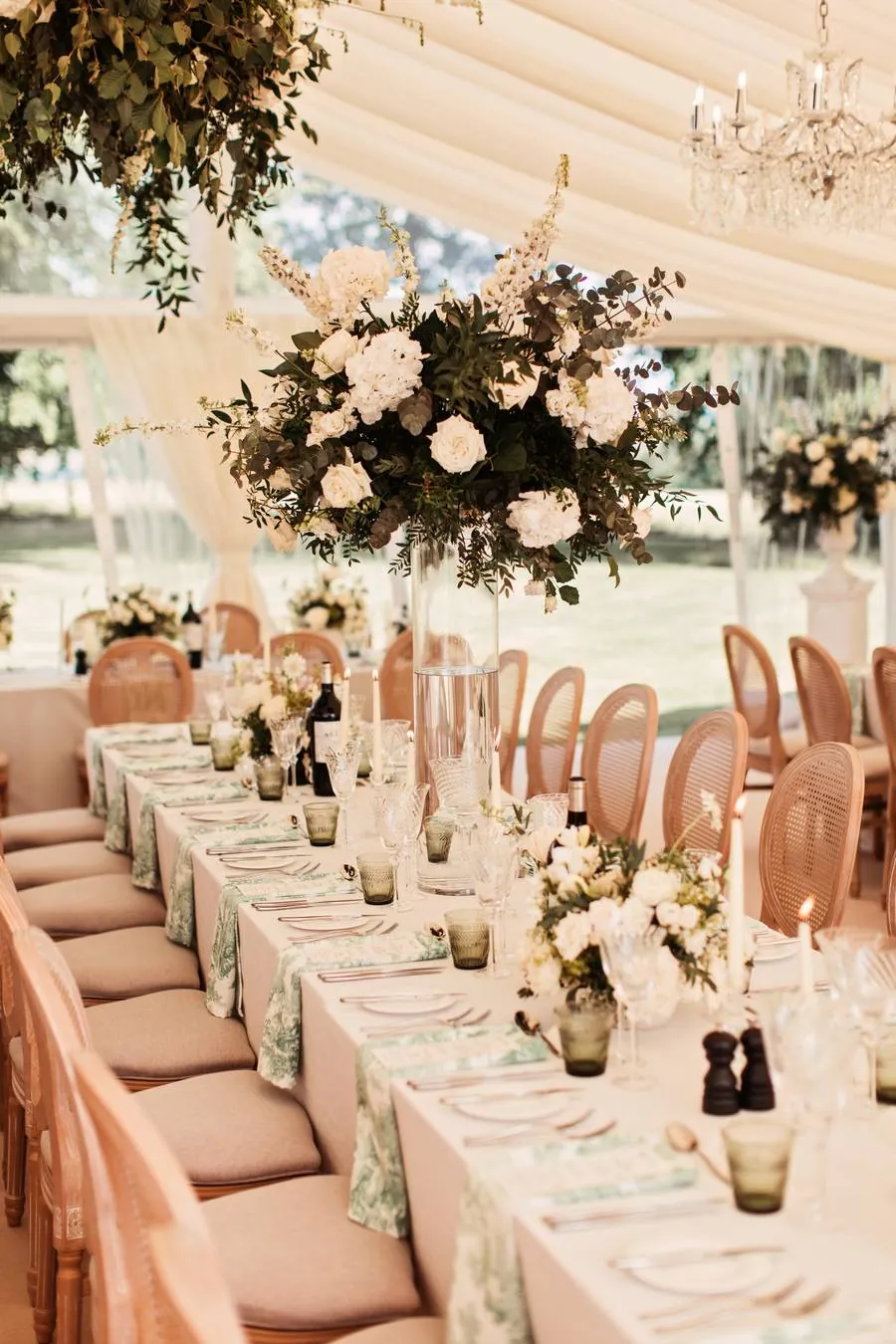 Long table with tall white floral centrepiece and chandelier