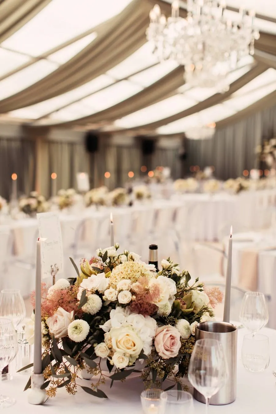 Low floral centrepiece with blush roses and pink smoke bush beneath a chandelier