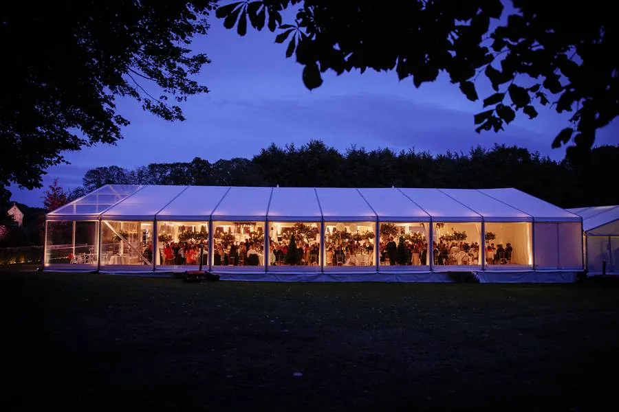 Marquee glowing at dusk with a dinner in full swing