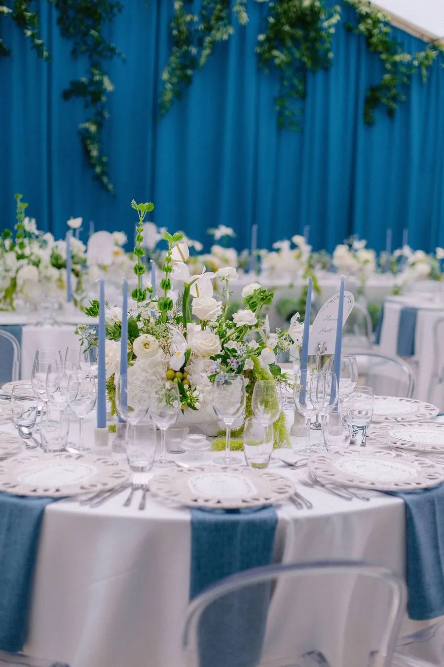 Round table with white flowers, blue candles and blue napkins