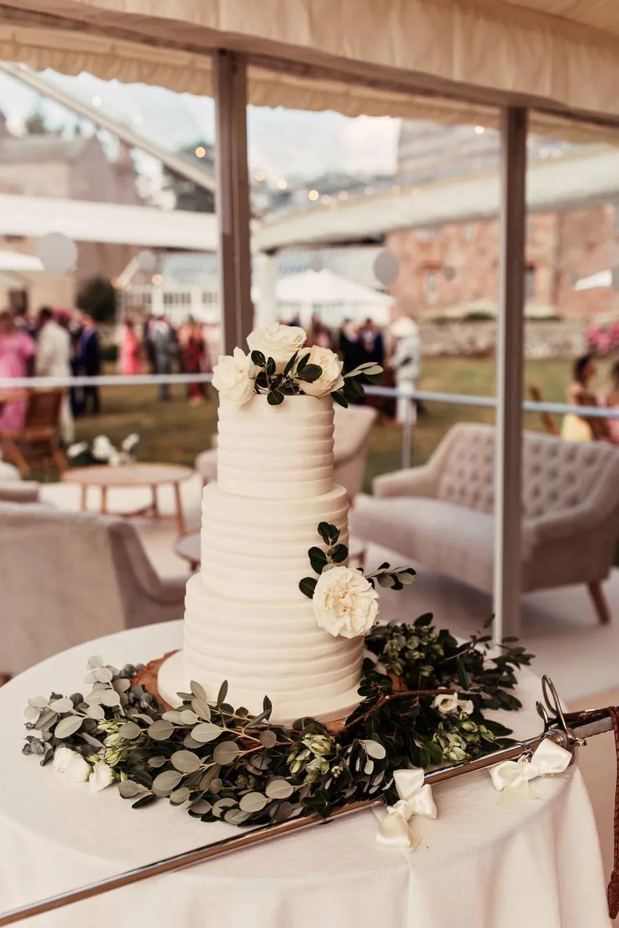 Simple white tiered wedding cake with roses and foliage