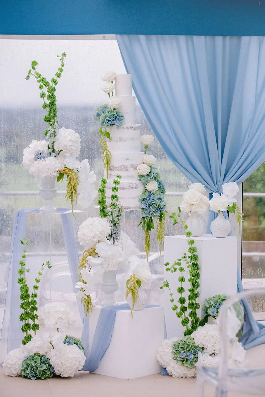 Tiered wedding cake surrounded by white and blue flowers