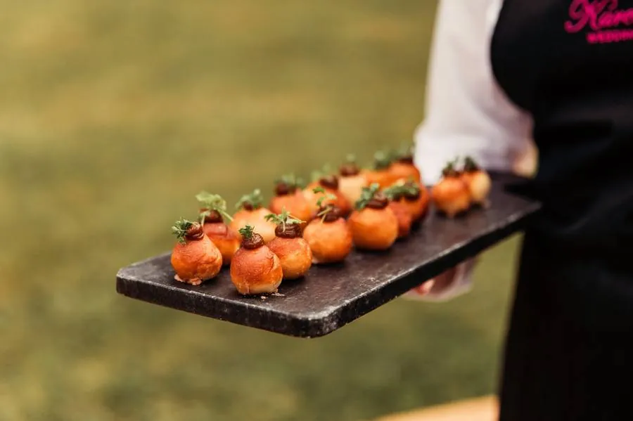 Tray of canapés being served on a slate board on the lawn