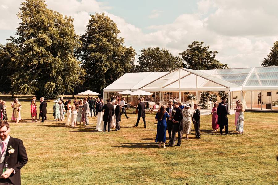 Wedding guests on the lawn beside a clear-topped marquee